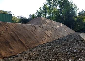 Travaux (octobre 2021) – Assainissement derrière les terrains de tennis avec la mise en place d’un géotextile de protection sur la butte du stand de tir en talus en remblais (état avant semis et plantations)